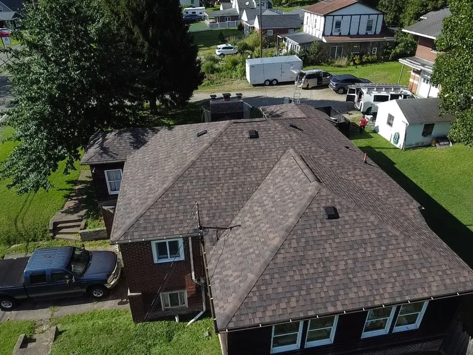 Aerial view of a finished architectural shingle roof with the crew's truck and trailer on site