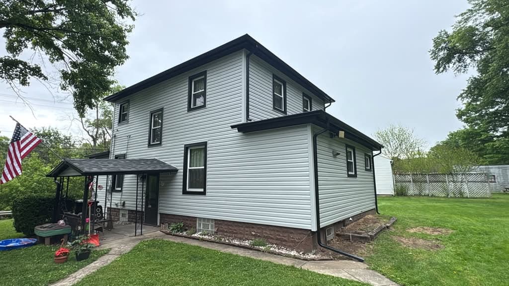 Wide angle of new white vinyl siding with black trim around windows